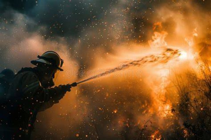 A firefighter sprays water after a fire devastated Clovemont Way, Bundoora in Melbourne