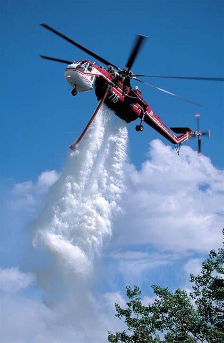 A helicopter drops water near homes in Yucaipa