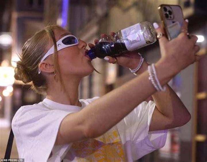 A reveller feeds booze to her pal through a beer bong