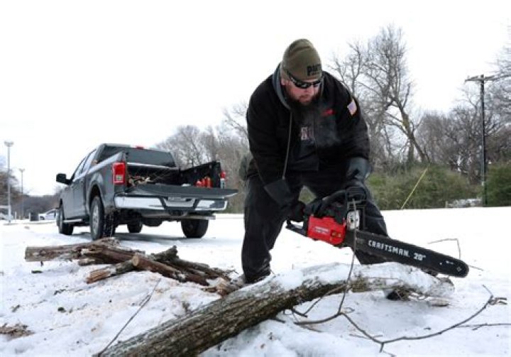 A Texan cuts up fallen wood in a park near his home which has been without power for more than 24 hours