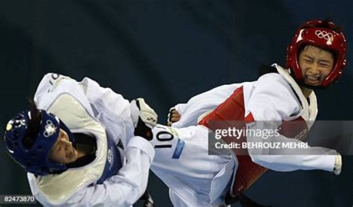  A woman lands a kick in her opponent's groin as they wrestle on the sands