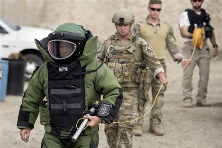 Bomb squad experts unload gear to check the site after a truck exploded into flames