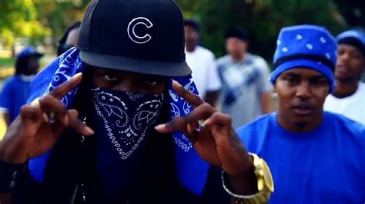 Crip members throwing up gang signs, and one man wears a bandanna to show his affiliation
