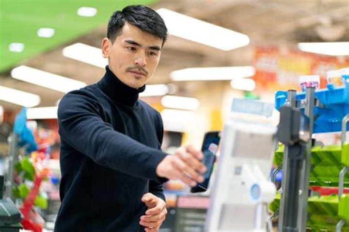 Customers scan their phones with orders on a kiosk and communicate with staff inside before pulling up to get their food
