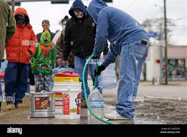 Jose Blanco fills a cooler with water from using a hose from a public park spigot