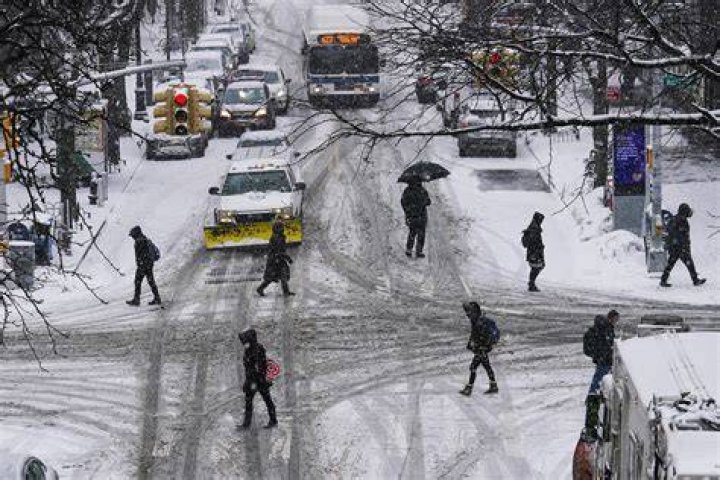 Pedestrians cross 71st Avenue, New York, as snow falls on Thursday