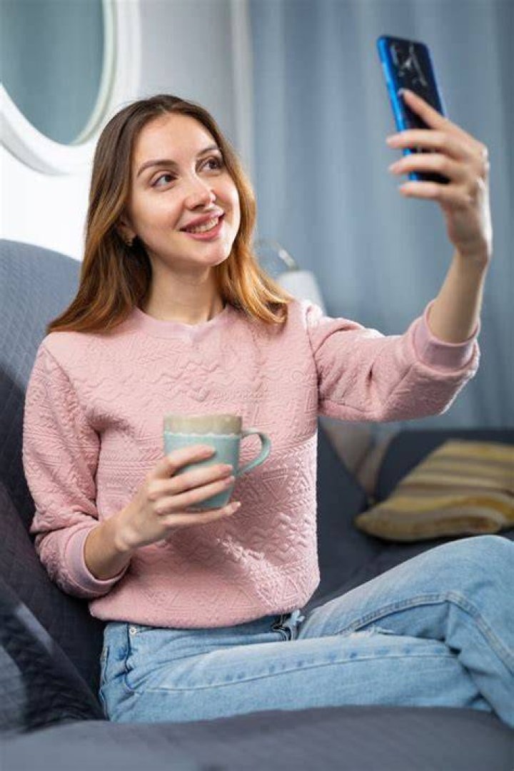 Smiling young woman using a smartphone in the city street on a lovely autumn day