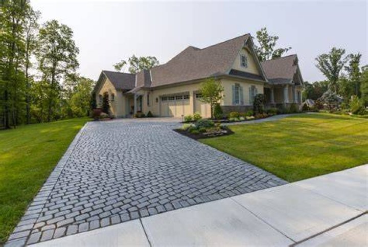 The paved driveways between the two homes are wide and lined with greenery