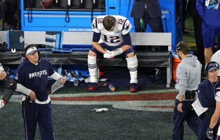 Tom Brady sitting on his Aston Martin DB11 he was gifted as part of his sponsorship deal with the automaker