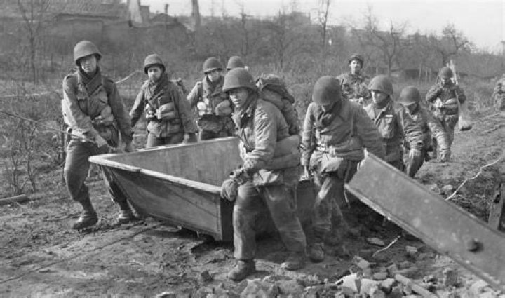  US Ninth Army soldiers cross to assault boats that engineers had laid across the Roer River for Operation Grenade