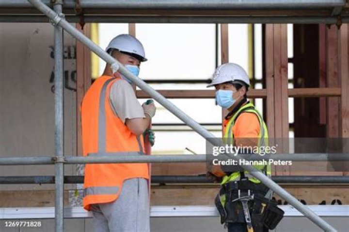 Workmen in face masks are seen outside the mansion